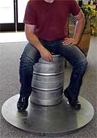 Grown man sitting on keg placed on Jaybird false bottom and stand